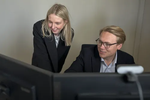 Bilde av to personer som jobber foran PC